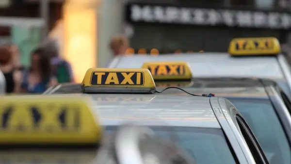Reihe von Taxis mit gelben Dachschildern. Die aktuellen Taxipreise sind auf den Schildern nicht sichtbar, aber die Fahrzeuge stehen bereit.