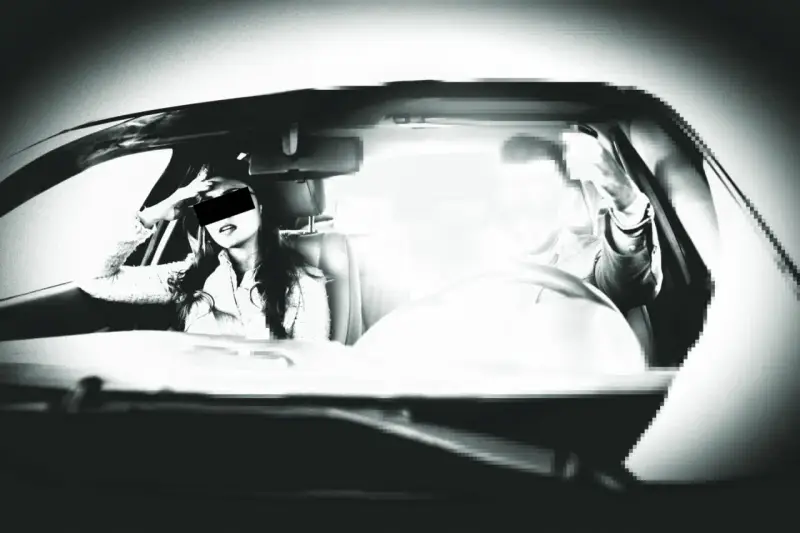 Frau im Auto, die sich die Hand ans Gesicht legt, während ein greller Blitz aufleuchtet. Ein blitzer foto, das die Szene einfängt.